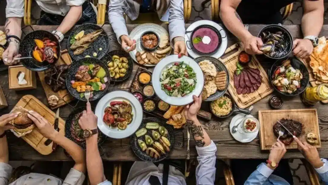 Skupina ľudí griluje na drevenom uhlí v záhrade