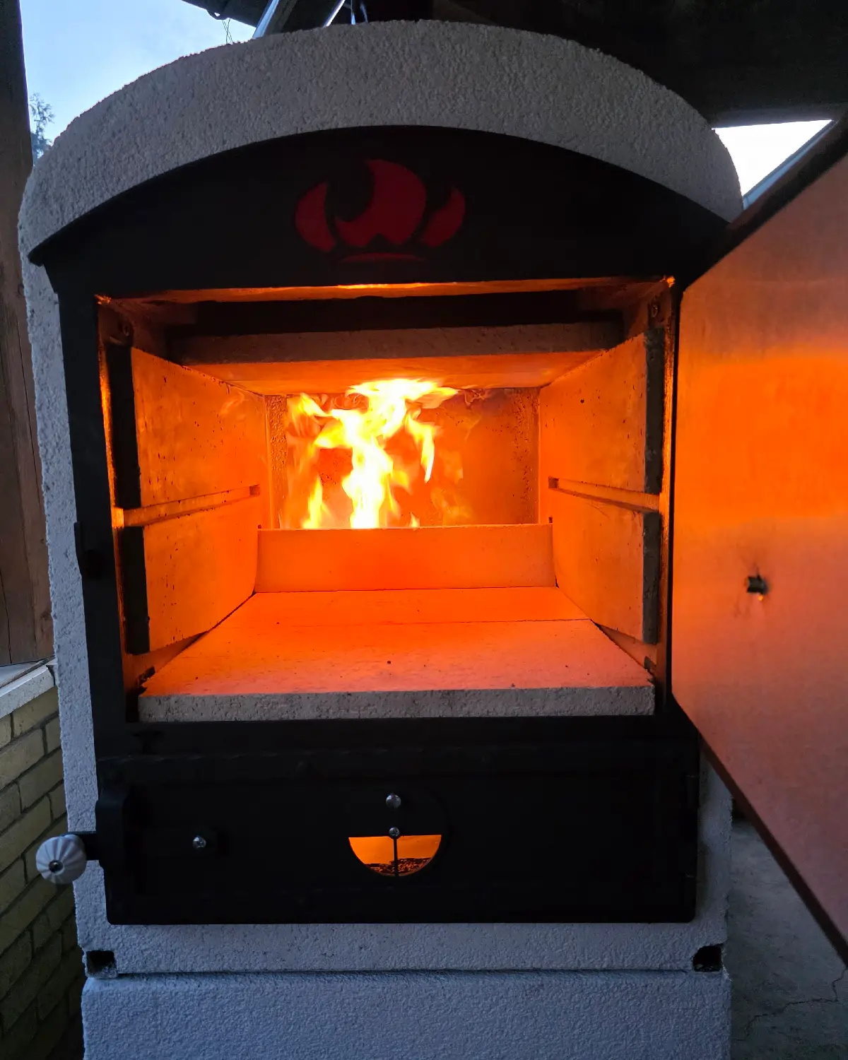Tynker heat-storage wood-fired oven in operation with live fire and active oven chamber