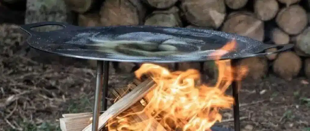 Seasoning a steel disc over an open fire